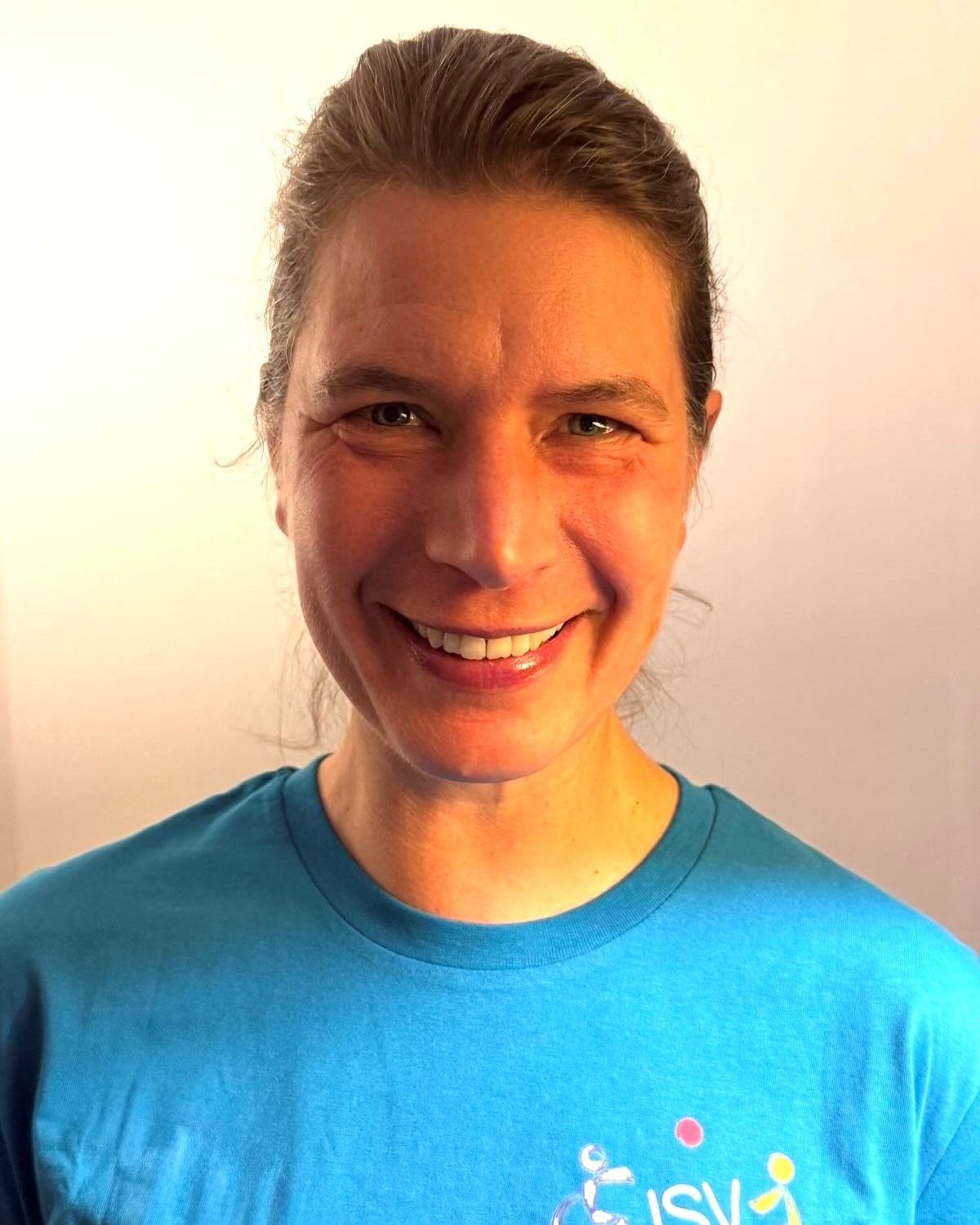 Eine Frau mit Pferdeschwanz lächelt freundlich in die Kamera und trägt ein ISV Alsterdorf T-Shirt.