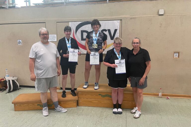 Badmintonspieler mit Medaillen und Urkunden stehen gemeinsam auf dem Siegerpodest.