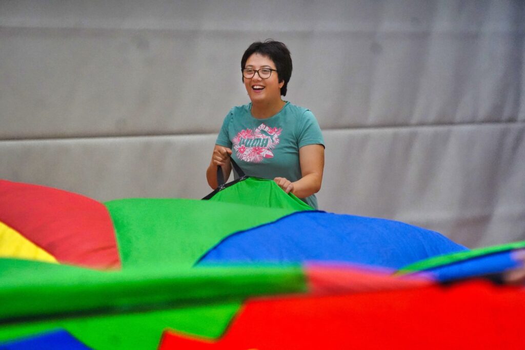 Eine Frau hält das bunte Schwungtuch fest und lacht während der gemeinsamen Übung.