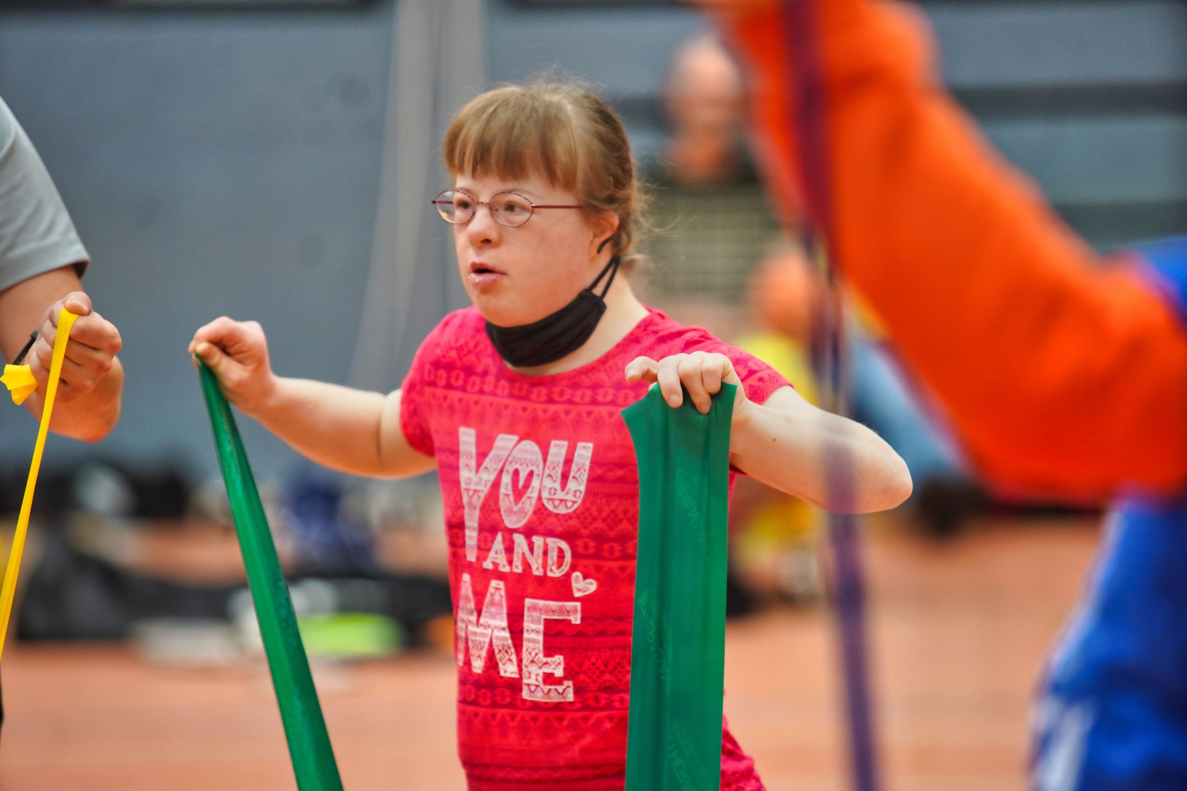 Ein Mädchen trainiert konzentriert mit grünen Widerstandsbändern während der Übungseinheit.